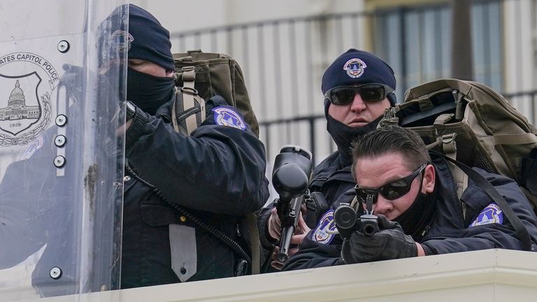 La police surveille les manifestants qui ont tenté de franchir une barrière policière, mercredi 6 janvier 2021, au Capitole à Washington.  Alors que le Congrès se prépare à affirmer la victoire du président élu Joe Biden, des milliers de personnes se sont rassemblées pour montrer leur soutien au président Donald Trump et à ses allégations de fraude électorale (AP Photo / John Minchillo)
