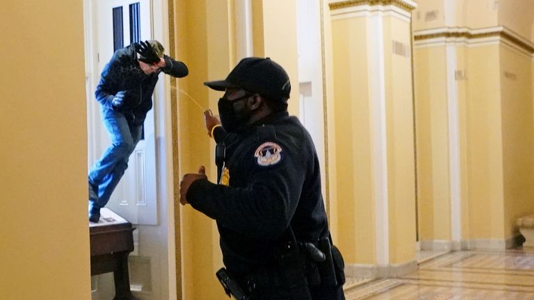 Un agent de police du Capitole américain tire du gaz poivré sur un manifestant qui tente d'entrer dans le bâtiment du Capitole lors d'une session conjointe du Congrès pour certifier les résultats des élections de 2020 au Capitole à Washington, États-Unis, le 6 janvier 2021. Kevin Dietsch / Pool via REUTERS TPX IMAGES DU JOUR