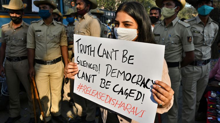 Un manifestant tient une pancarte en faveur de Mme Ravi à côté d'une file de policiers à Bangalore