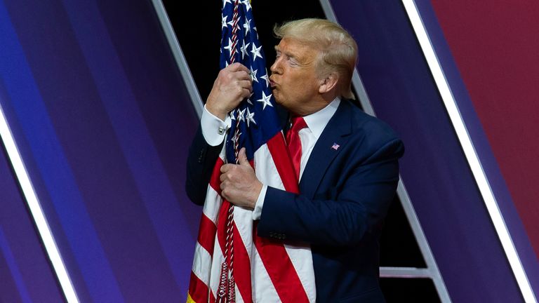 Donald Trump embrasse le drapeau américain après avoir pris la parole à la Conférence d'action politique conservatrice, CPAC 2020. Pic: AP