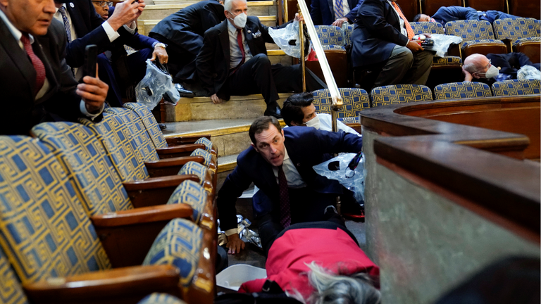 Les gens s'abritent dans la galerie de la Chambre alors que les manifestants tentent de s'introduire dans la salle