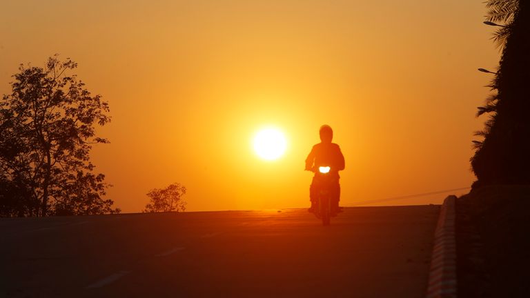 Un homme chevauche sa moto pendant le coucher du soleil à Naypyitaw, au Myanmar.  Pic: AP