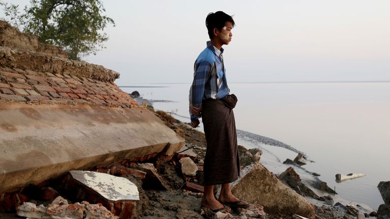 Un étudiant se tient près des décombres d'une école après qu'elle s'est effondrée dans l'eau au Myanmar