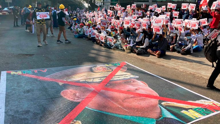 Une grande image qui a une marque X sur le visage du commandant en chef général Min Aung Hlaing, également président du Conseil administratif de l'État, se trouve sur la route alors que les manifestants anti-coup d'État se rassemblent devant le centre Hledan à Yangon, au Myanmar dimanche, février 14, 2021. Les manifestations de masse quotidiennes de rue au Myanmar en sont à leur deuxième semaine, ni les manifestants ni le gouvernement militaire qu'ils cherchent à renverser ne montrant des signes de recul face aux affrontements.  (Photo AP) ....
