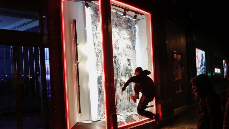 Un manifestant ouvre la fenêtre d'un magasin alors que les partisans du rappeur catalan arrêté Pablo Hasel manifestent à Barcelone, en Espagne, le 20 février 2021. REUTERS / Albert Gea TPX IMAGES DU JOUR