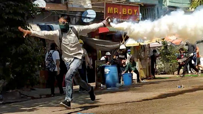 Un manifestant court avec une cartouche de gaz lacrymogène lors d'une manifestation à Yangon