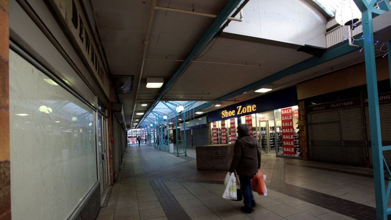 Une femme passe devant Shoe Zone, l'un des seuls magasins restants ouverts dans l'extrémité nord du centre commercial Southside à Wandsworth, Londres, où les magasins sont fermés en attente de réaménagement.