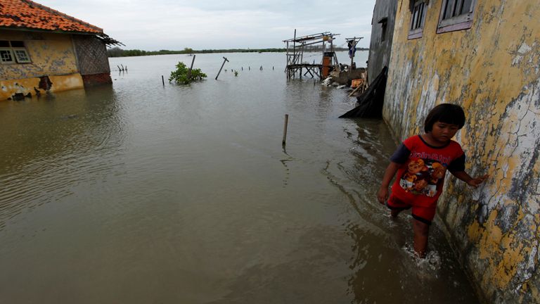Un enfant marche à côté de sa maison dans une rue inondée d'eau de mer dans le village mayangan de Subang, province de Java occidental en Indonésie, le 16 juillet 2010