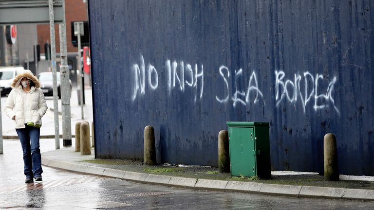 Une femme passe devant un graffiti disant `` Pas de frontière de la mer d'Irlande '' dans le centre-ville de Belfast, en Irlande du Nord