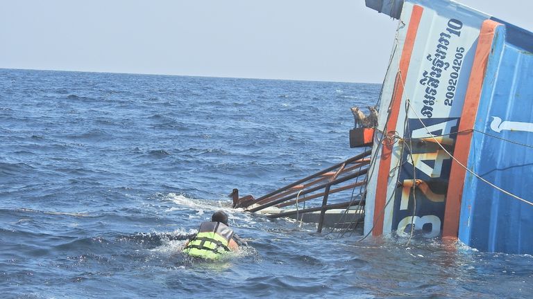Un officier de la marine thaïlandaise nage vers des chats debout sur un bateau qui coule pour les sauver lors de la marche de la mer d'Andaman.  PIC: PO1 Wichit Pukdeelon via Reuters