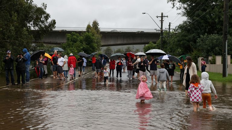Les gens se rassemblent dans une rue résidentielle inondée près de la rivière Nepean gonflée alors que l'état de la Nouvelle-Galles du Sud subit des inondations généralisées