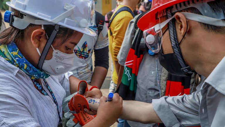 Un manifestant anti-coup d'État écrit des informations d'urgence vitales sur un autre manifestant sur son bras à Yangon, au Myanmar, mercredi 3 mars 2021. Les manifestants au Myanmar sont descendus à nouveau dans les rues mercredi pour protester contre la prise du pouvoir par l'armée le mois dernier.  (Photo AP)