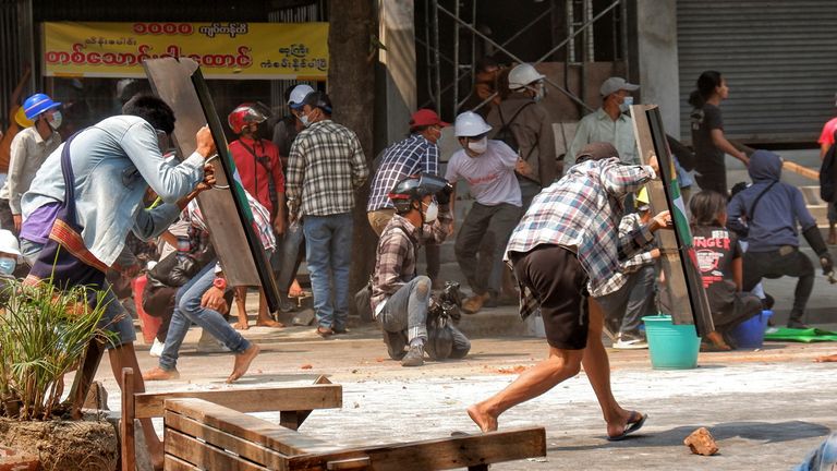 Les manifestants couvrent avec des boucliers de fortune lors d'une manifestation anti-coup d'État à Mandalay, Myanmar