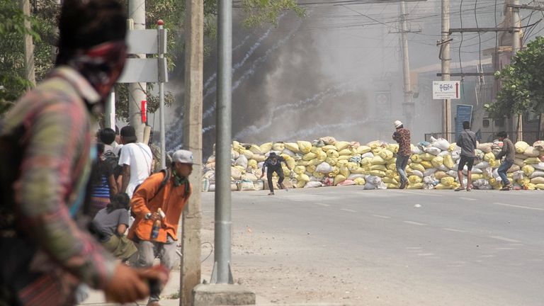 Des manifestants se mettent à couvert derrière une barricade lors d'une manifestation anti-coup d'État à Mandalay, au Myanmar