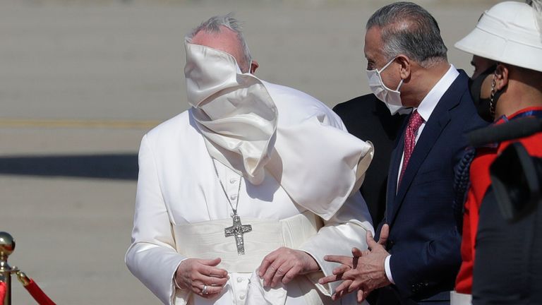 Une rafale de vent souffle sur le manteau du pape François alors qu'il se tient aux côtés du Premier ministre irakien Mustafa al-Kadhimi à son arrivée à l'aéroport international de Bagdad, en Irak, le vendredi 5 mars 2021. Le pape François se rend en Irak vendredi pour exhorter le pays à diminuer le nombre de Les chrétiens doivent rester sur place et aider à reconstruire le pays après des années de guerre et de persécution, en écartant la pandémie de coronavirus et les problèmes de sécurité.  (Photo AP / Andrew Medichini)