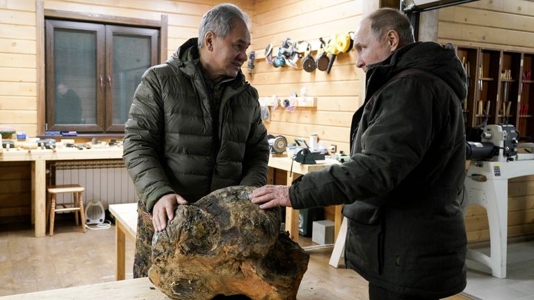 Le ministre russe de la Défense, Sergei Shoigu, à gauche, et le président russe Vladimir Poutine se parlent et examinent un morceau de bois à fabriquer dans l'atelier de Sergei Shoigu dans une forêt de la taïga de la région de Sibérie en Russie. 