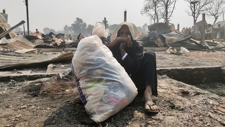 Une femme rohingya est assise par terre avec ses effets personnels après que son abri a été incendié