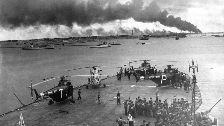 Troupes et hélicoptères sur le pont de l'un des premiers navires de la Royal Navy à entrer à Port-Saïd, en Égypte, qui est vu enveloppé de fumée et de feu après sa capture.  11/11/1956