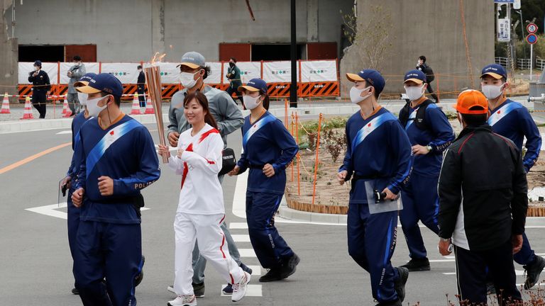 Un porteur de flambeau passe devant un bâtiment abandonné à Fukushima