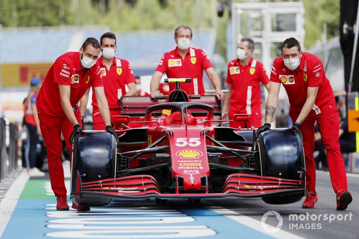 Des mécaniciens Ferrari poussent la voiture de Carlos Sainz Jr., Ferrari SF21, le long de la voie des stands
