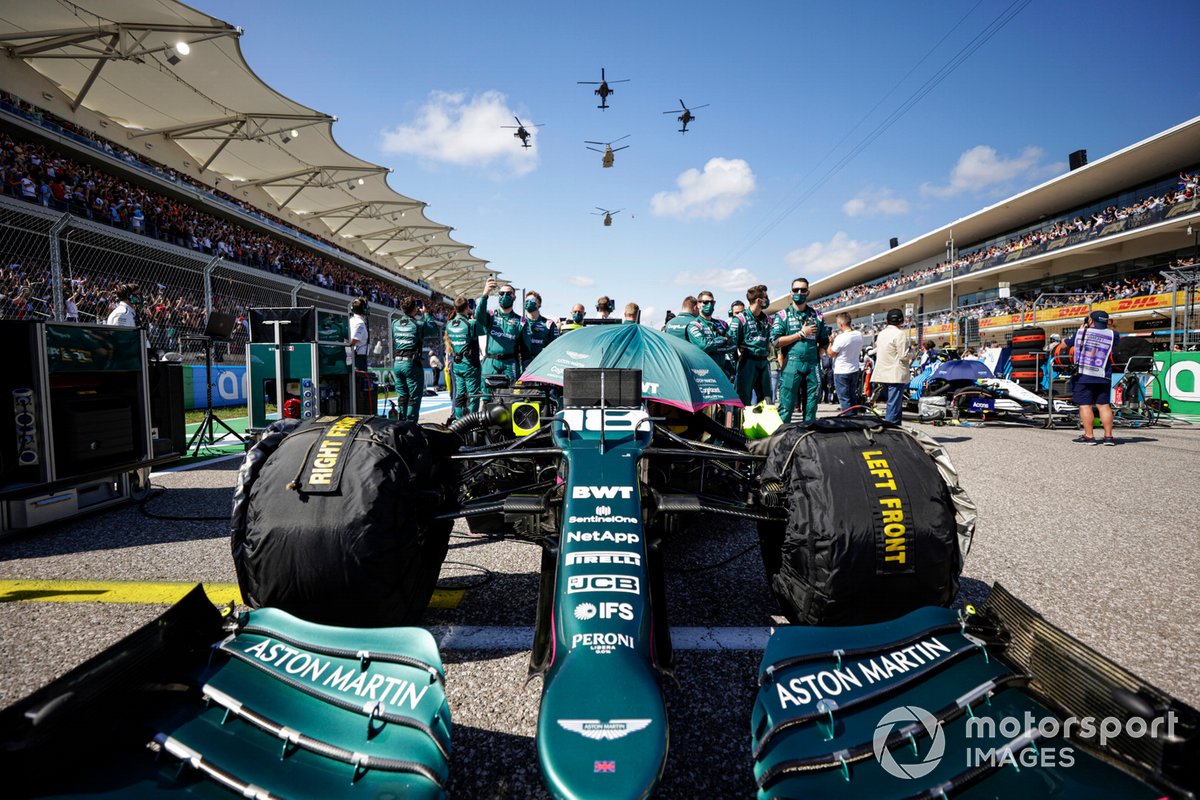 Les membres de l'équipe Aston Martin sur la grille avec la voiture de Lance Stroll, Aston Martin AMR21, alors qu'un quintette d'hélicoptères de l'armée américaine survole la grille avant le départ